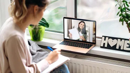 Mujer tomando notas durante una videoconferencia.