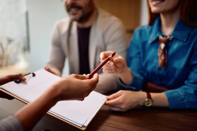 Pareja firmando un contrato de compraventa con abogada inmobiliaria