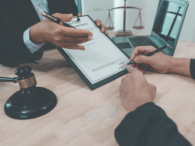 Manos de un abogado mercantil explicando un contrato a otra persona