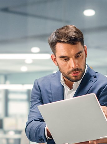 Joven Gerente hablando con otra gerente con experiencia mientras se utiliza un ordenador portátil en Office.