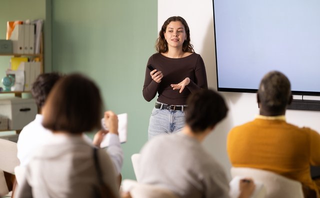 Mujer docente dando una clase frente a sus alumnos