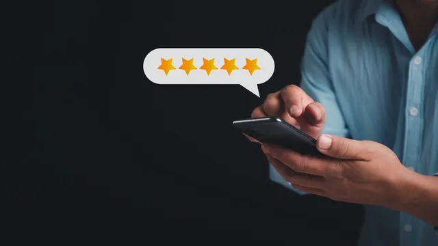 Las manos de una persona con un móvil colocando reseña de cinco estrellas expresado en pop up