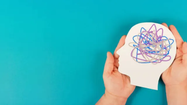 An image of two hands gently holding a white paper cutout of a human head profile on a bright blue background.