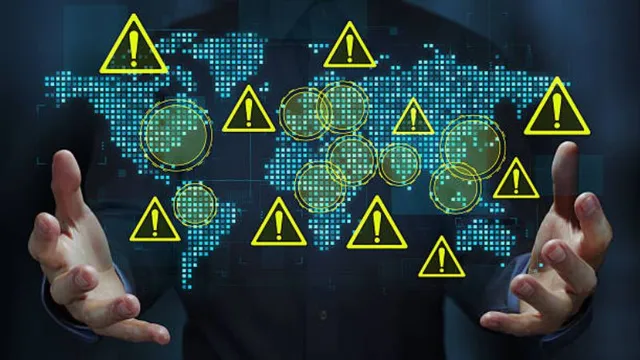A person holds open hands framing a digital glowing world map overlaid with numerous yellow warning icons containing exclamation marks.