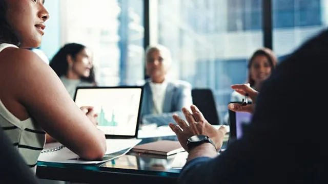 Diverse corporate finance team discussing financial performance charts in a modern boardroom meeting.