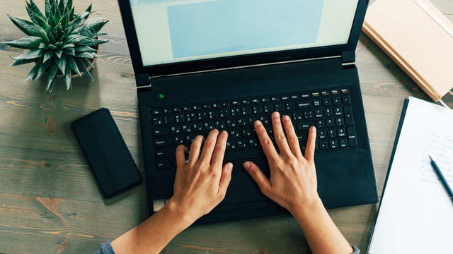 vista cenital de unas manos apoyadas en el teclado de un ordenador port&aacute;til
