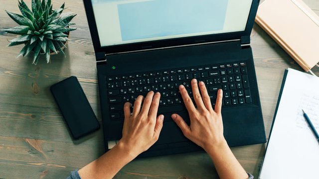 vista cenital de unas manos apoyadas en el teclado de un ordenador portátil