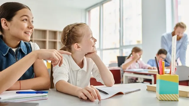 dos niñas, rodeadas de libros y útiles escolares, participan en un debate en clase