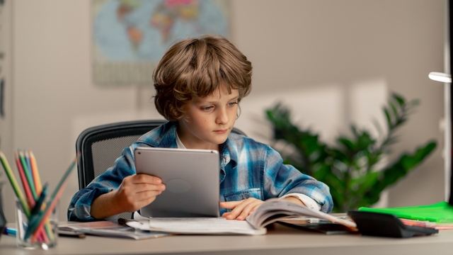 niño sentado detrás de un escritorio y haciendo los deberes