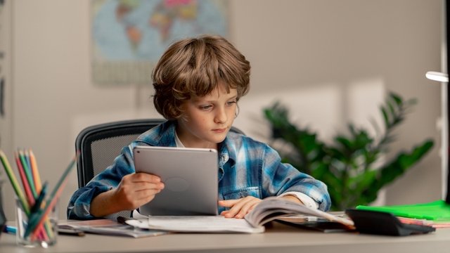 niño sentado detrás de un escritorio y haciendo los deberes