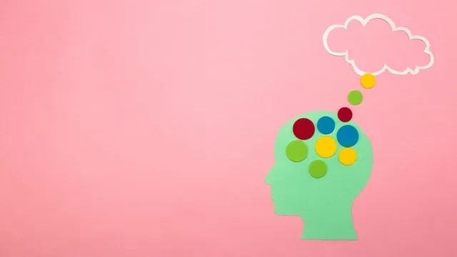cabeza de papel verde sobre fondo rosa de la que salen unos puntos coloridos que terminan en una nube de pensamiento