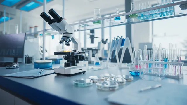 laboratorio de investigación con microscopio y tubos de prueba con bioquímicos en el escritorio