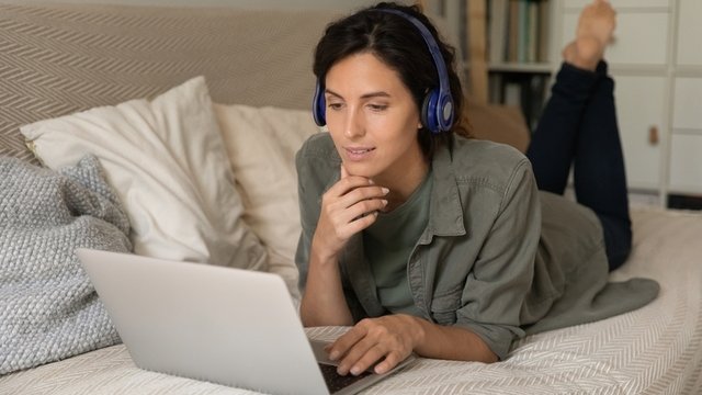 mujer relajada con auriculares en el sofá, viendo películas en el ordenador portátil