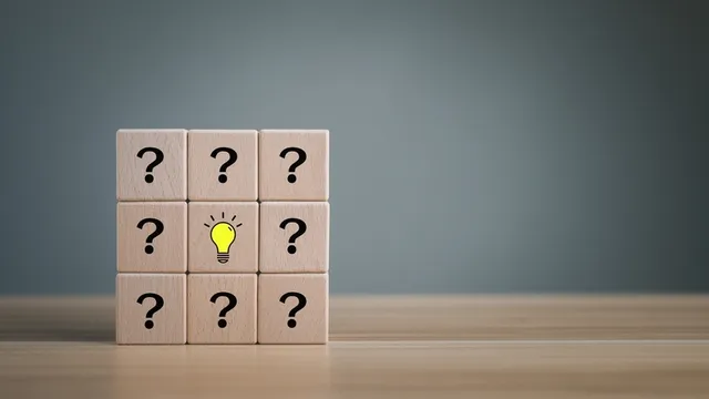 un cubo de madera con muchos signos de interrogación y bombillas