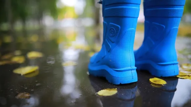 piernas de niño con botas de agua azules saltando charcos