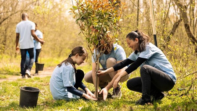 alumna y profesores plantando juntos un árbol