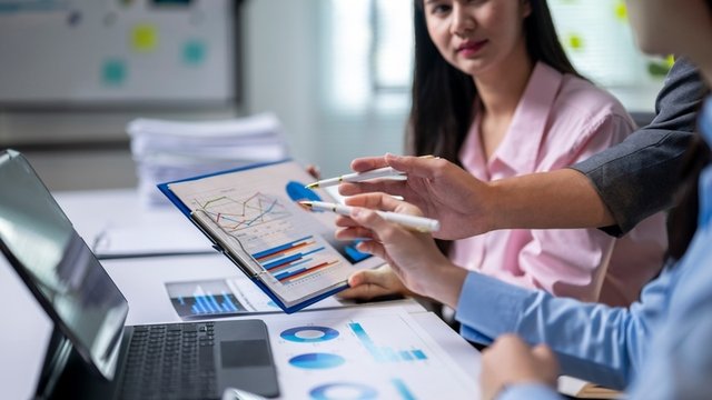 un grupo de personas está discutiendo los datos de unos gráficos y toma decisiones basadas en ellos