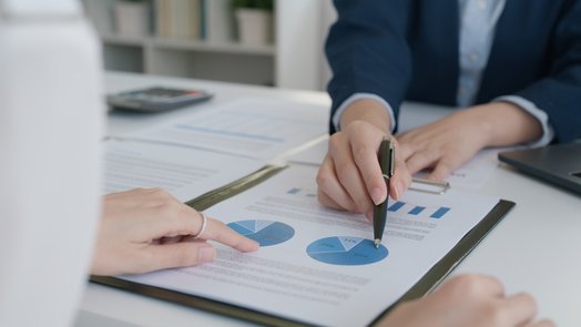 dos personas reunidas en un despacho revisan los gráficos de unos documentos