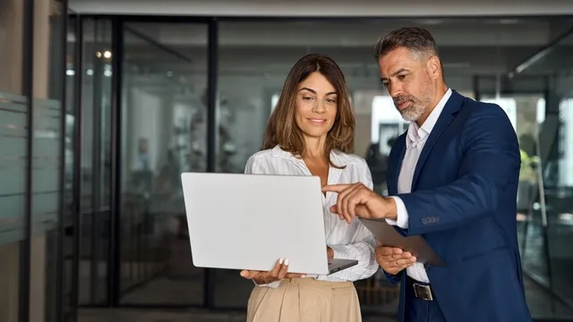 hombre y mujer discuten algo sobre un proyecto frente a la pantalla de un ordenador portátil