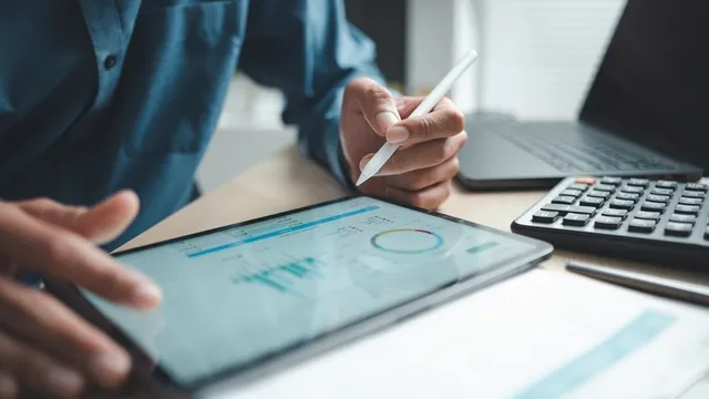 Profesional de negocios que analiza datos financieros en tablero digital con calculadora y computadora portátil