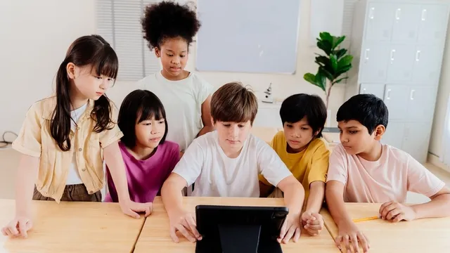varios estudiantes de Educación Primaria observan un vídeo con una tableta en el aula