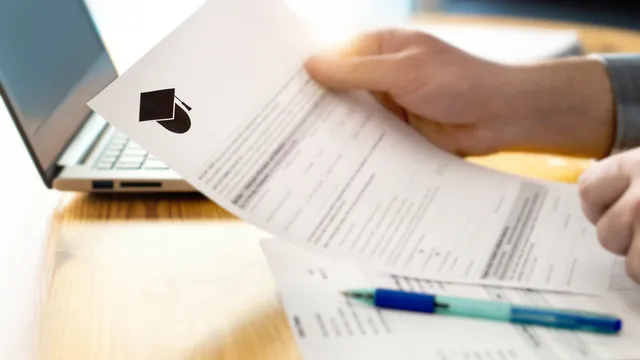 persona sostiene en la mesa un documento de solicitud de beca