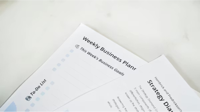 top-down view of printed business documents, including a "Weekly Business Planner" with a to-do list