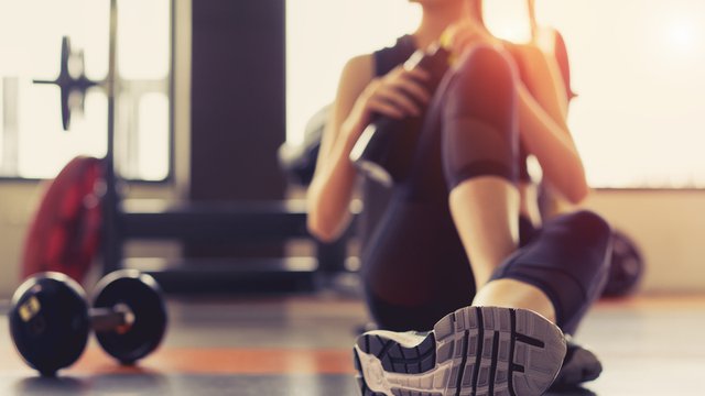 persona sentada en el suelo de un gimnasio después de hacer ejercicio