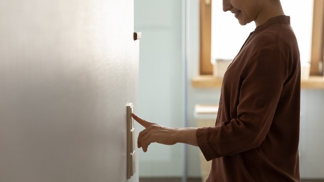 mujer encendiendo o apagando el interruptor de la luz situado en una pared