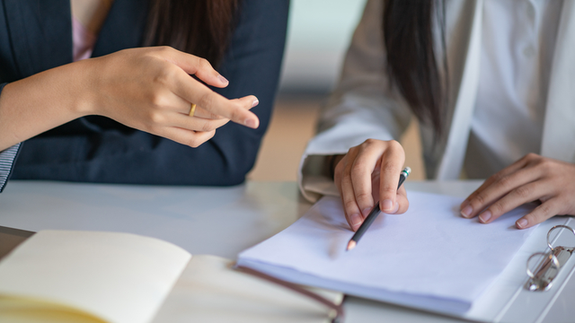 dos personas revisan una documentaci&oacute;n antes de firmarla