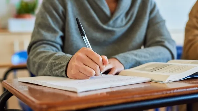 estudiante universitario toma apuntes en una libreta, mientras lee un libro