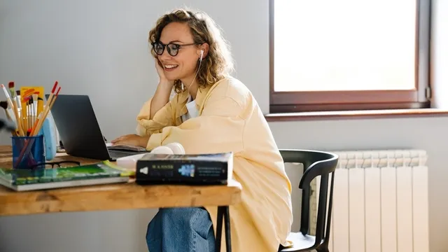 chica sentada en un escritorio revisando un escrito en su ordenador portátil
