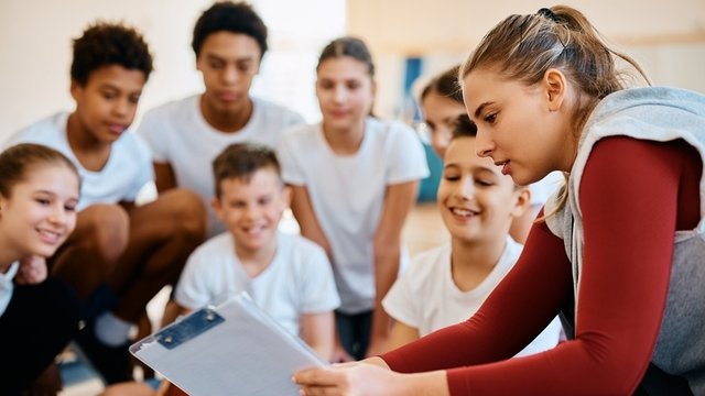 profesora de educación física enseñando un plan de ejercicio a sus alumnos