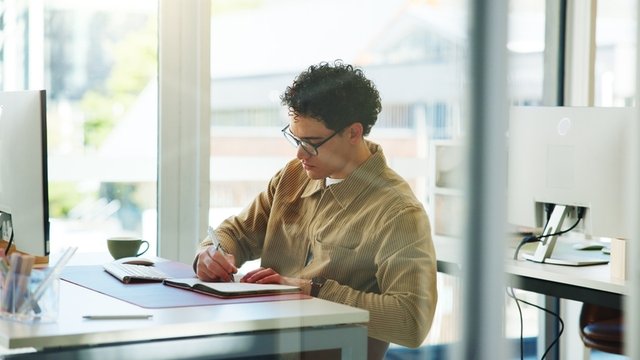 hombre sentado en una oficina escribiendo en una libreta