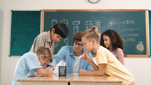 pedagogo da las pautas del trabajo que tienen que hacer a unos estudiantes de Educación Primaria