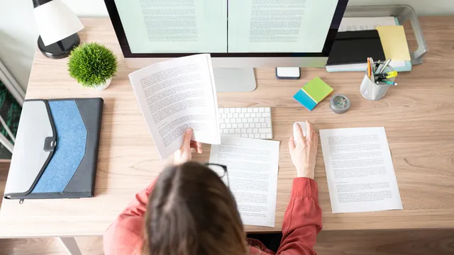 traductora sentada frente a un ordenador revisa los documentos de una traducción