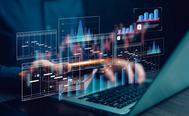 A person types on a laptop while digital data visualisations including Gantt charts, bar graphs, and financial analytics float above the keyboard.