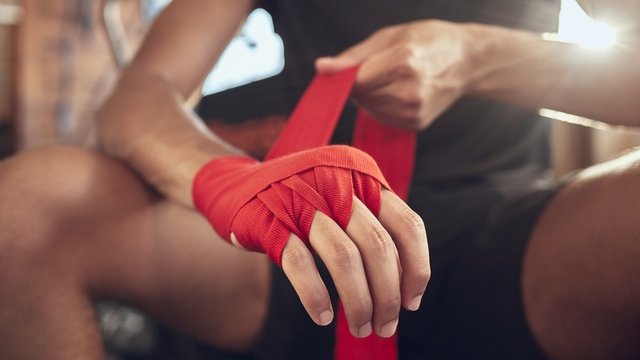 hombre boxeador envolviéndose la mano con un vendaje antes de colocarse los guantes