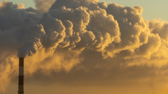 la chimenea de una fábrica liberando emisiones de carbono