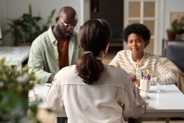 vista trasera de una trabajadora social que atiende a un padre y a su hijo en un despacho