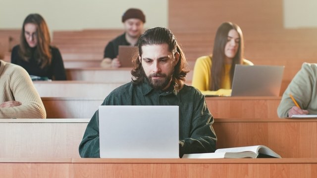 estudiante sentado en un aula universitaria usando un ordenador portátil