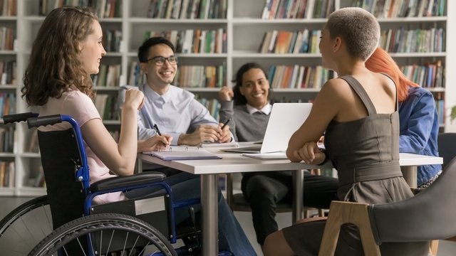 chica joven en silla de ruedas acompañada de sus compañeros de clase