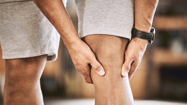 manos apoyadas alrededor de una rodilla por culpa del dolor