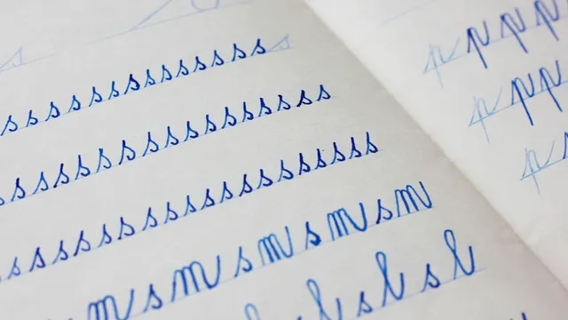 primer plano de letras azules escritas en cursiva por un niño en un cuaderno de papel con líneas