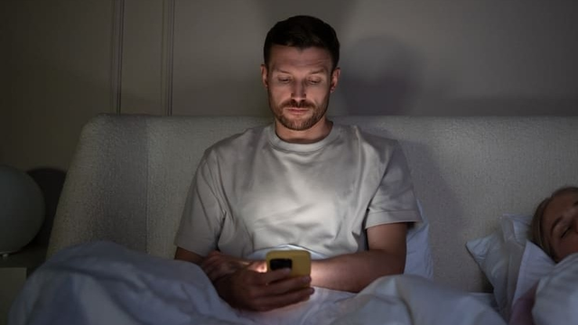 persona en la cama haciendo scroll con el móvil