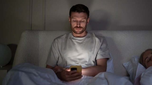 persona en la cama haciendo scroll con el móvil