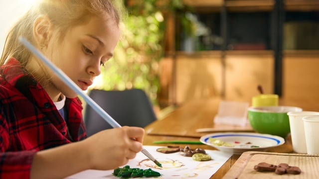chica pintando de color verde unas manualidades hechas con arcilla