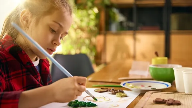 chica pintando de color verde unas manualidades hechas con arcilla