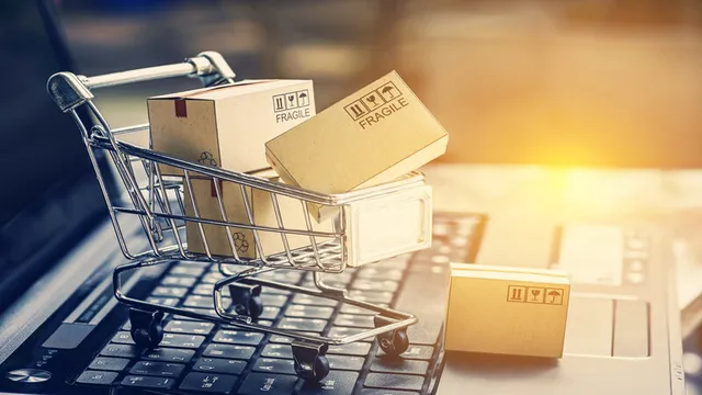 carro de la compra repleto de cajas de cartón sobre el teclado de un ordenador portátil