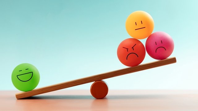 caras emocionales coloridas que se equilibran en un balancín